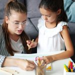 Mother and daughter drawing together at a table.