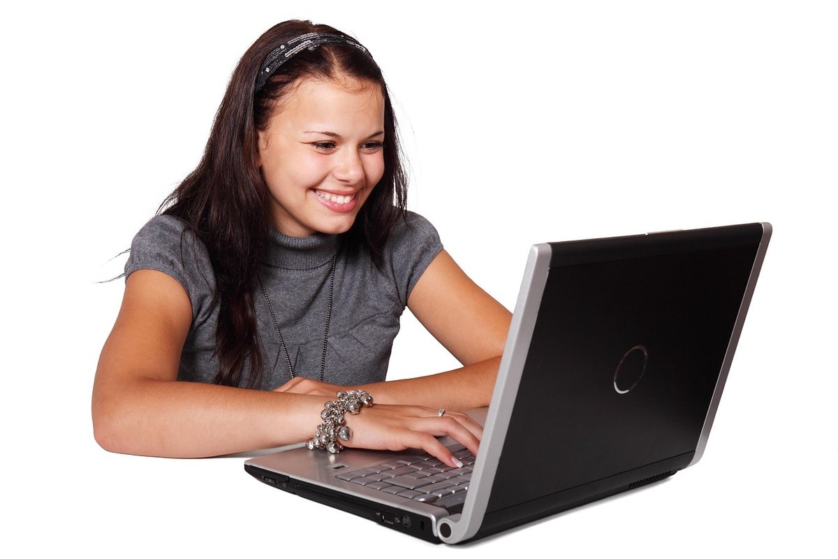 Femme souriante utilisant un ordinateur portable, visage tourné vers l'écran