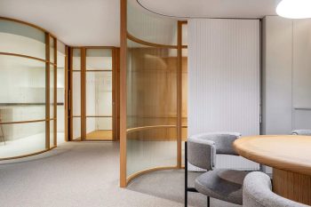 Salle intérieure avec table ronde, chaises, cloisons en verre et porte en bois